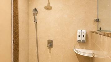 A modern bathroom with a walk-in shower, a handheld showerhead, a wall-mounted faucet, and a soap dispenser.