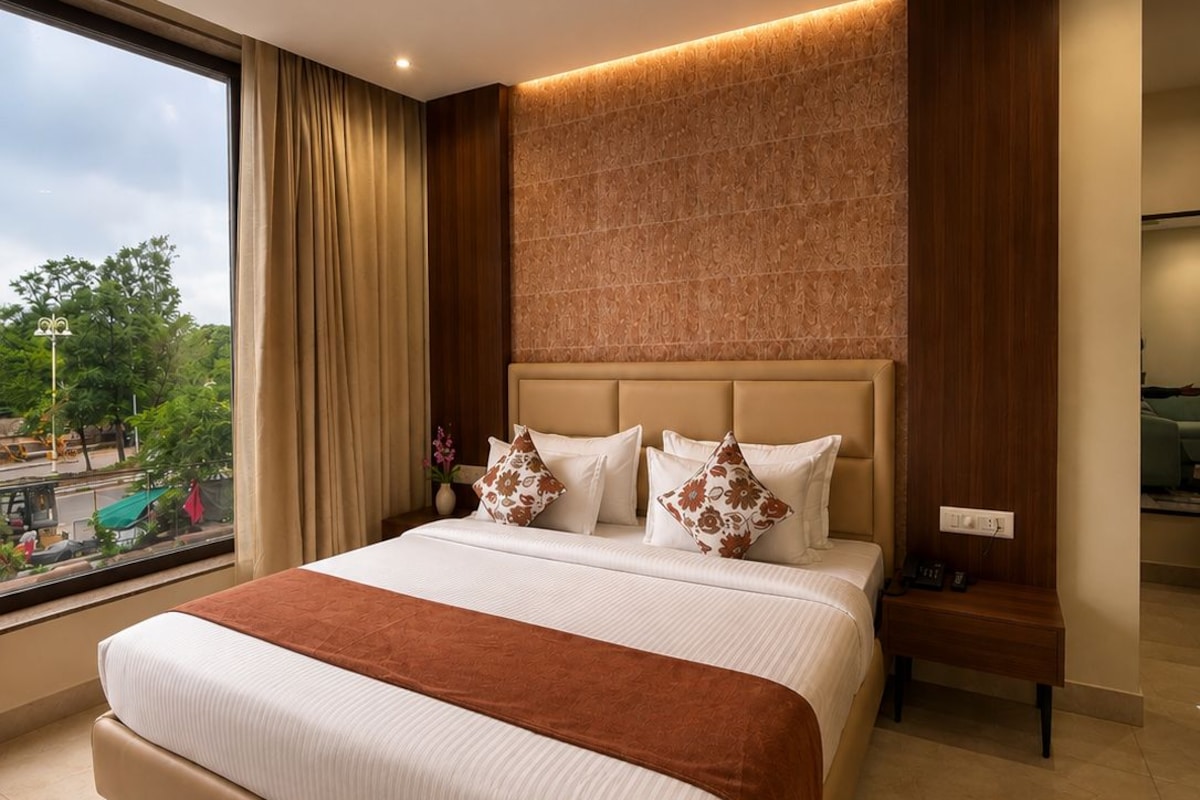 Habitación de hotel con una cama grande, ventilador de techo, mesita de noche y vistas al exterior.