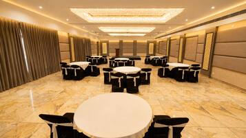 A conference room with round tables and chairs, a large chandelier, and a marble floor.
