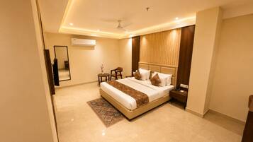 A modern hotel room with a large bed, bedside tables, a small seating area, and a ceiling fan.
