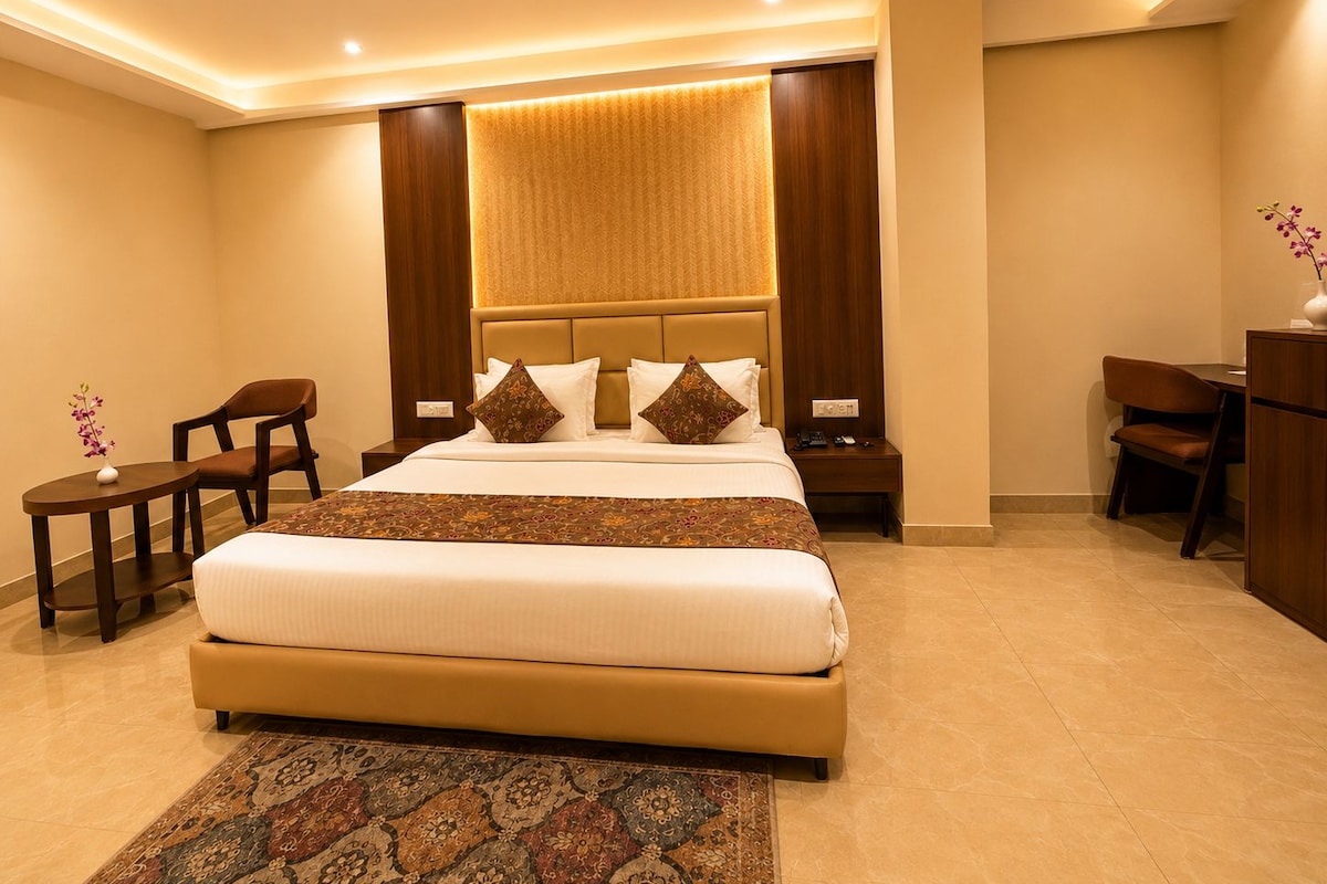 Habitación de hotel con una cama grande, un escritorio, una silla, una mesita de noche y un ventilador de techo.