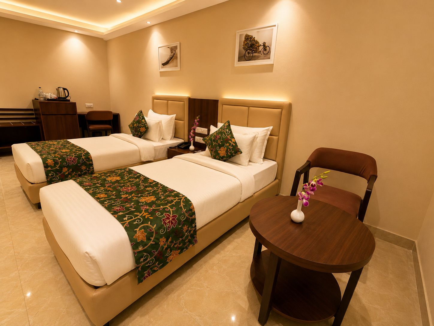 A hotel room with two beds, a small table, and a chair.