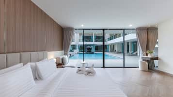 Habitación de hotel moderna con una cama grande, vistas a una zona de piscina y un balcón.