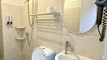 Casa de banho com sanita, lavatório, espelho e chuveiro.