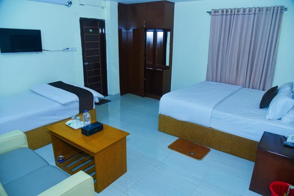 A hotel room with two beds, a desk, a TV, and a wardrobe.