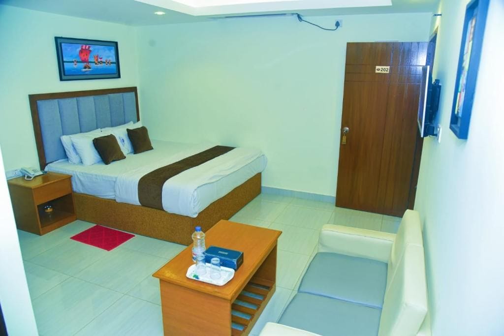 A hotel room with a bed, bedside table, chair, and a door marked with the number 202.