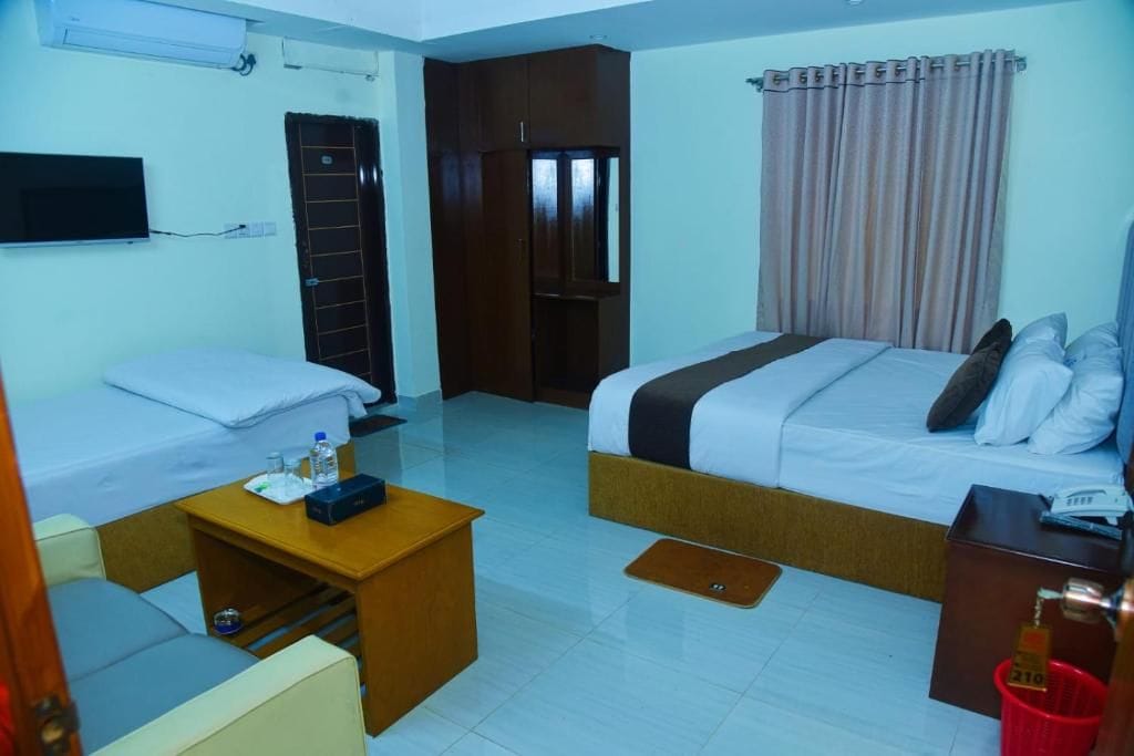 A hotel room with a bed, a desk, a chair, a TV, and a wardrobe.