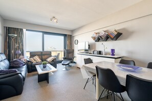 A modern living room with a sofa, coffee table, and a dining area with chairs and a table. - Apartment in Blankenberge Near Belgium Pier (Blankenberge)