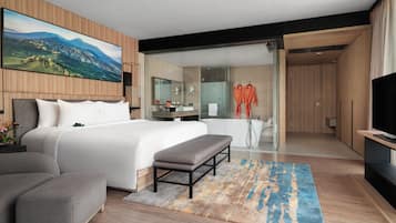 Een moderne hotelkamer met een groot bed, een zithoek, een badkamer met douche en een televisie.