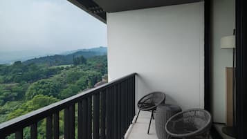 Ein Balkon mit Blick auf eine üppige Landschaft, zwei Korbstühle und ein kleiner Tisch.