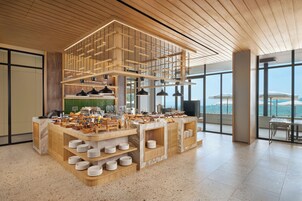 Una barra de desayuno moderna con diversas opciones de comida y vista al mar.