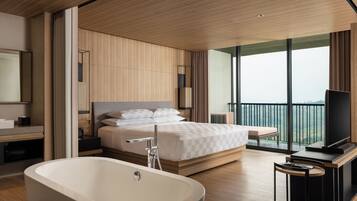 Een moderne hotelkamer met een groot bed, een badkuip, een televisie en een balkon met uitzicht.