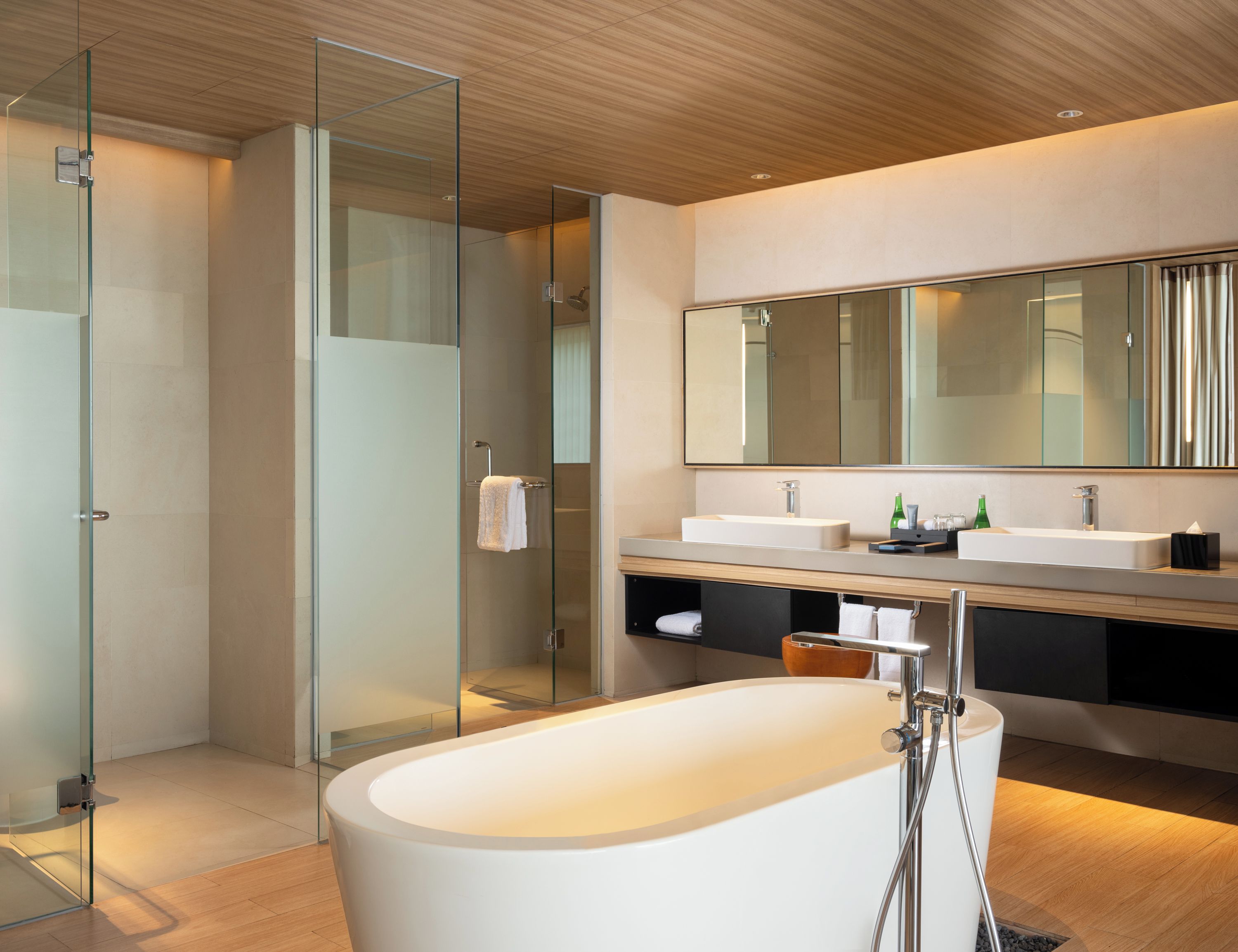 A modern bathroom with a freestanding bathtub, glass shower enclosure, and a large mirror above the vanity.