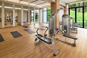 Un gimnasio con equipamiento de ejercicio, suelo de madera y amplias ventanas.