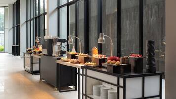 A buffet setup with various food items, a coffee machine, and a beverage dispenser.