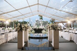 An indoor venue with a glass ceiling, tables set for dining, and floral decorations. - Angsana Bogor Gunung Geulis (Bogor)