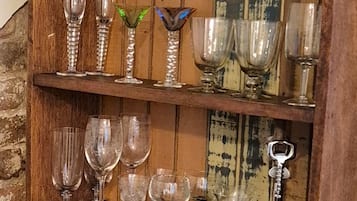 A wooden shelf with various glassware and mugs.