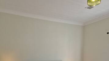 A bedroom with a bed, two bedside lamps, a wooden headboard, and a hanging light fixture.