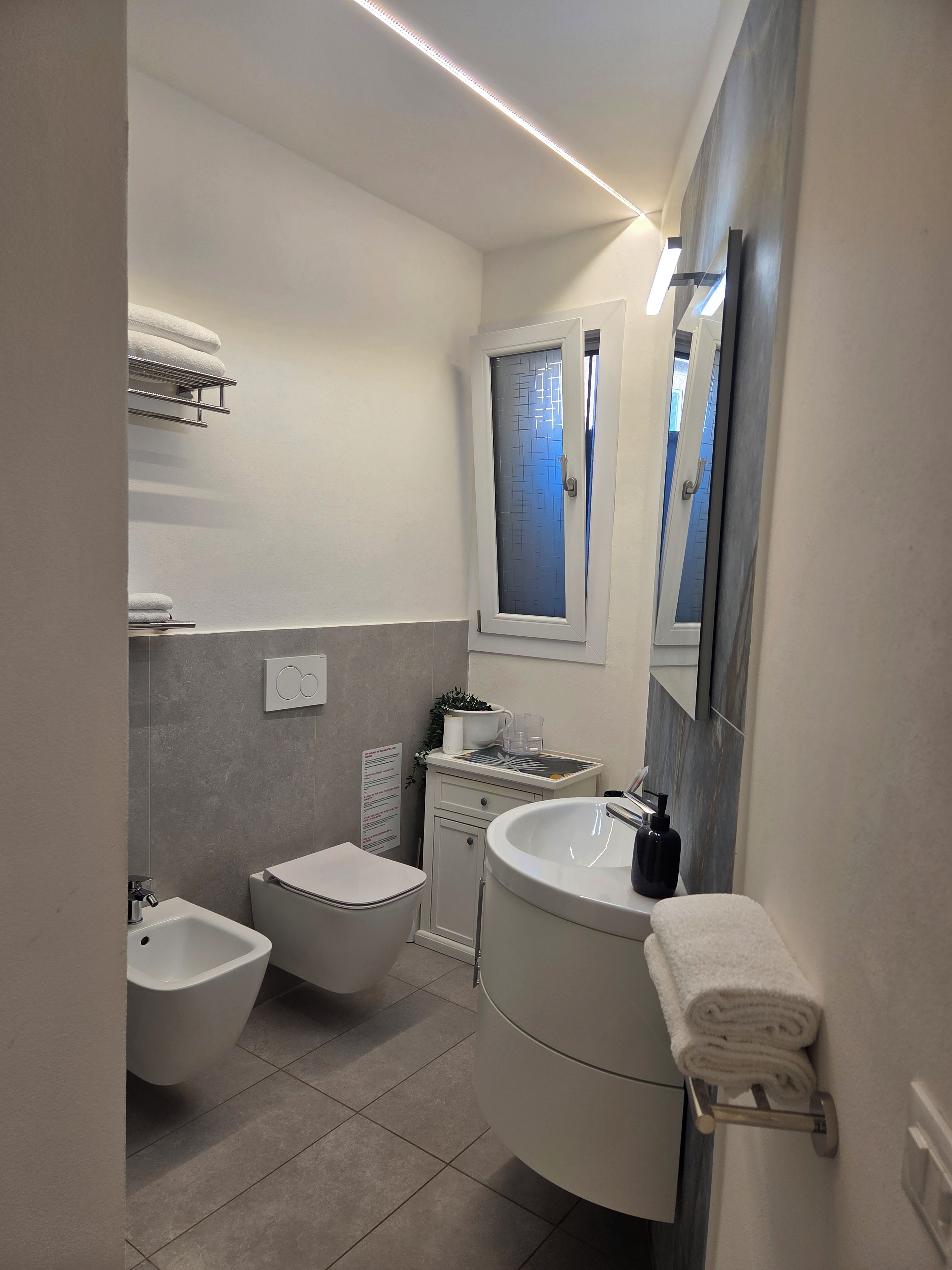 Ein modernes Badezimmer mit Toilette, Bidet, Waschbecken und Spiegel.