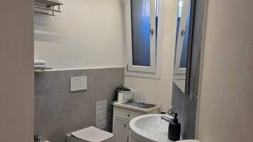 Ein modernes Badezimmer mit Toilette, Bidet, Waschbecken und Spiegel.