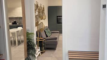 A modern living room with a sofa, a bench, and a dining area with a table and chairs.