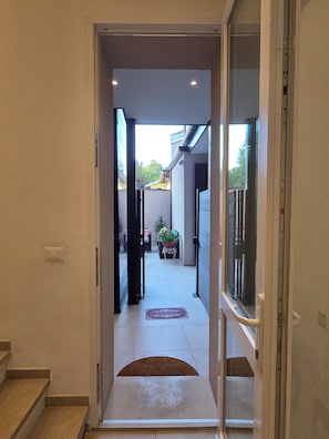 Un pasillo que conduce a un patio con una planta en maceta y un banco.