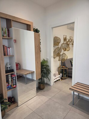 A modern interior with a wooden bookshelf, a potted plant, a small table, and a decorative wall piece.