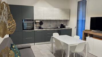 Una cucina moderna con zona pranzo, pensili grigi e un televisore a schermo piatto.