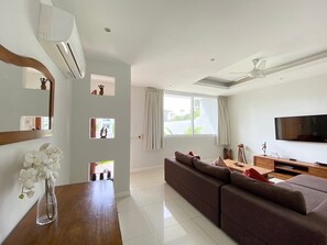 A modern living room with a sofa, TV, and a ceiling fan. - Townhouse Walking to the Beach (Koh Samui)