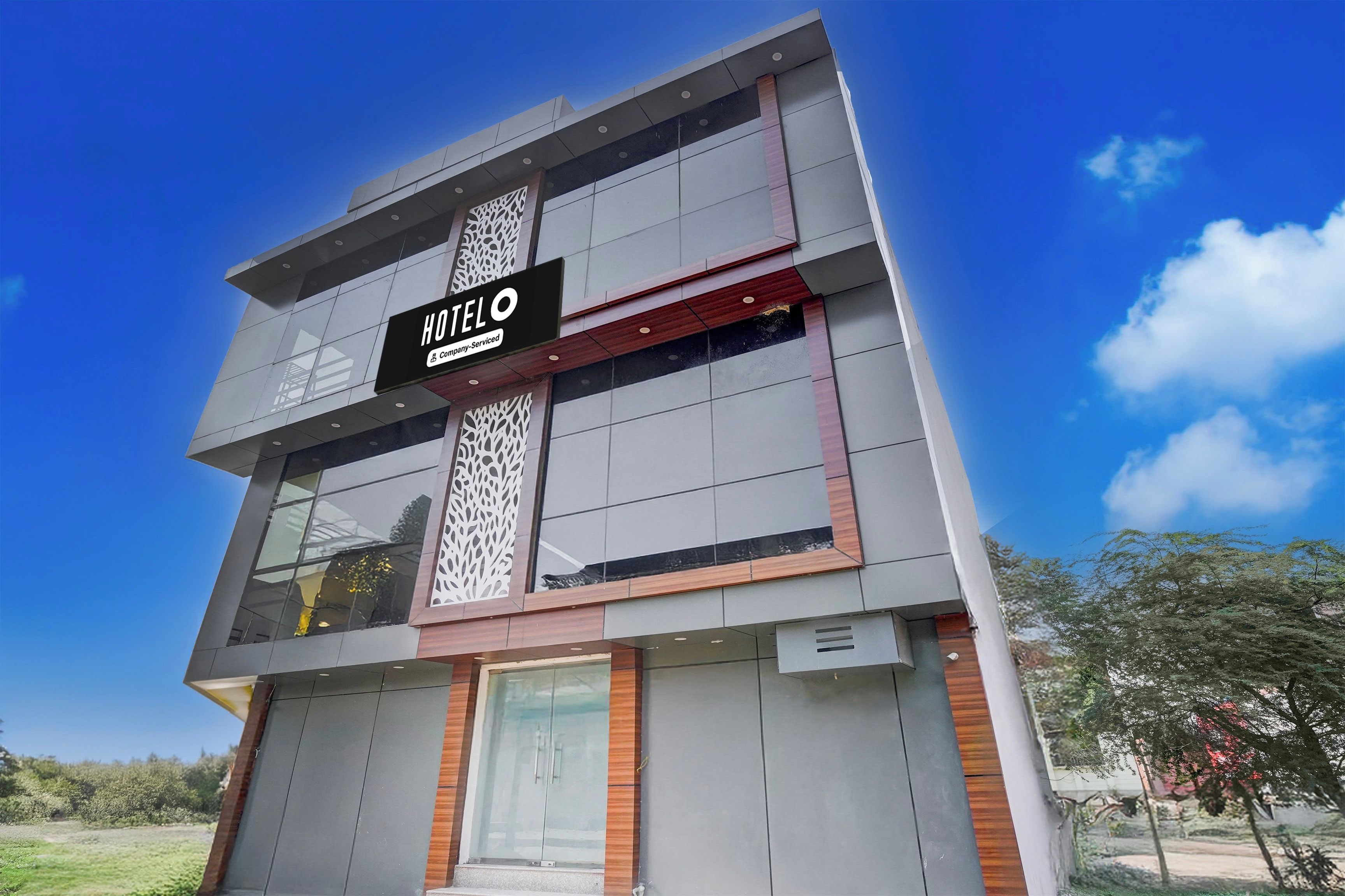 Un hôtel moderne, avec un bâtiment imposant et une enseigne bien visible indiquant « HÔTEL O », ainsi que le logo de l’entreprise.