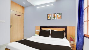 A hotel room with a bed, a nightstand, a wall-mounted light, and a door. - OYO Hotel O Gomti Nagar Near Amity (Lucknow)