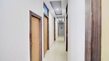 A corridor with doors on both sides, a tiled floor, and a ceiling with recessed lighting.