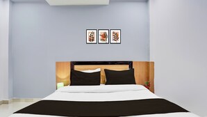 A hotel room with a bed, a nightstand, a lamp, and three framed pictures on the wall. - OYO Hotel O Gomti Nagar Near Amity (Lucknow)