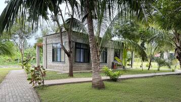 A small, single-story building with a brick exterior, surrounded by a well-maintained lawn and palm trees.