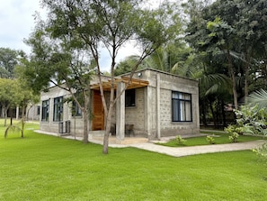 A modern house with a stone facade, a wooden door, and a covered porch. - Nagira Tranquility (Taveta)