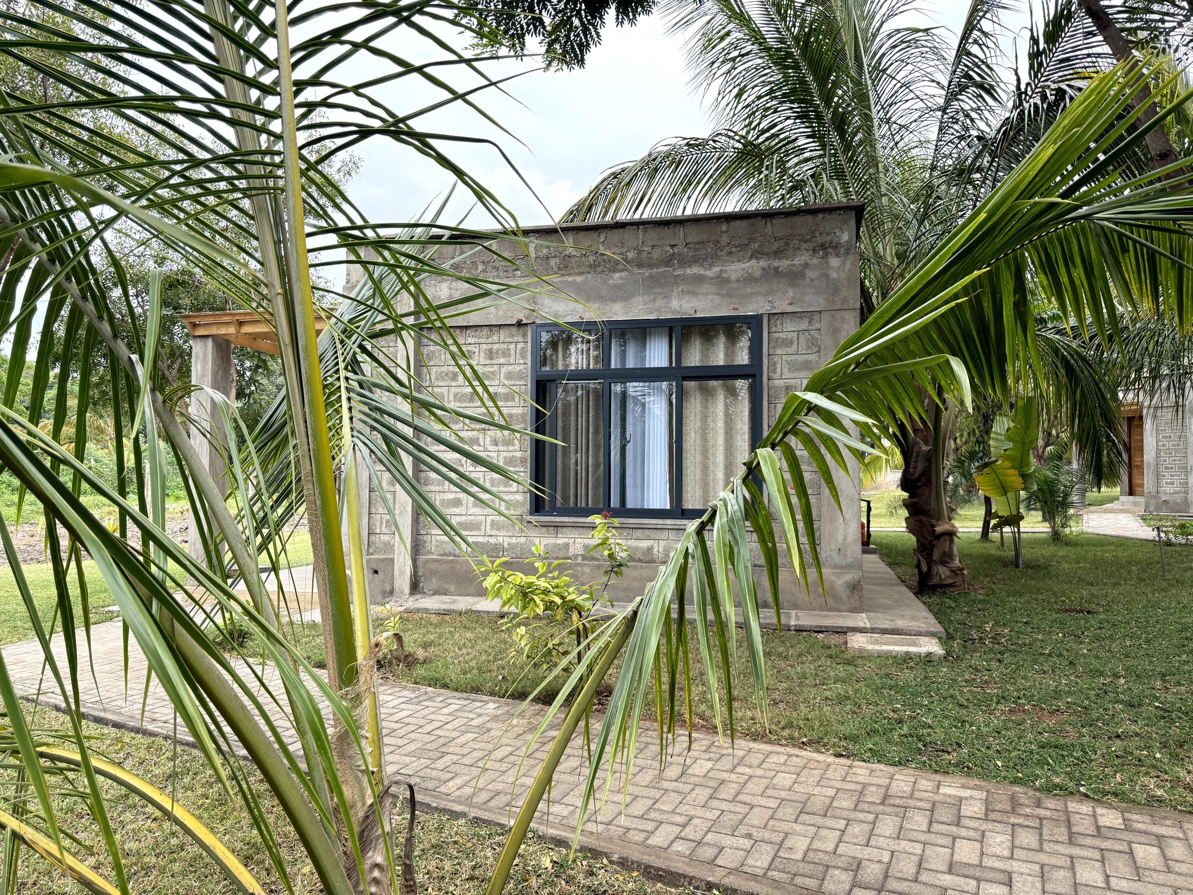 Un edificio moderno con fachada de piedra, un gran ventanal y un camino pavimentado que conduce hacia él.