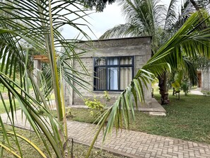Un edificio moderno con fachada de piedra, un gran ventanal y un camino pavimentado que conduce hacia él.