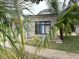 Un edificio moderno con fachada de piedra, un gran ventanal y un camino pavimentado que conduce hacia él.
