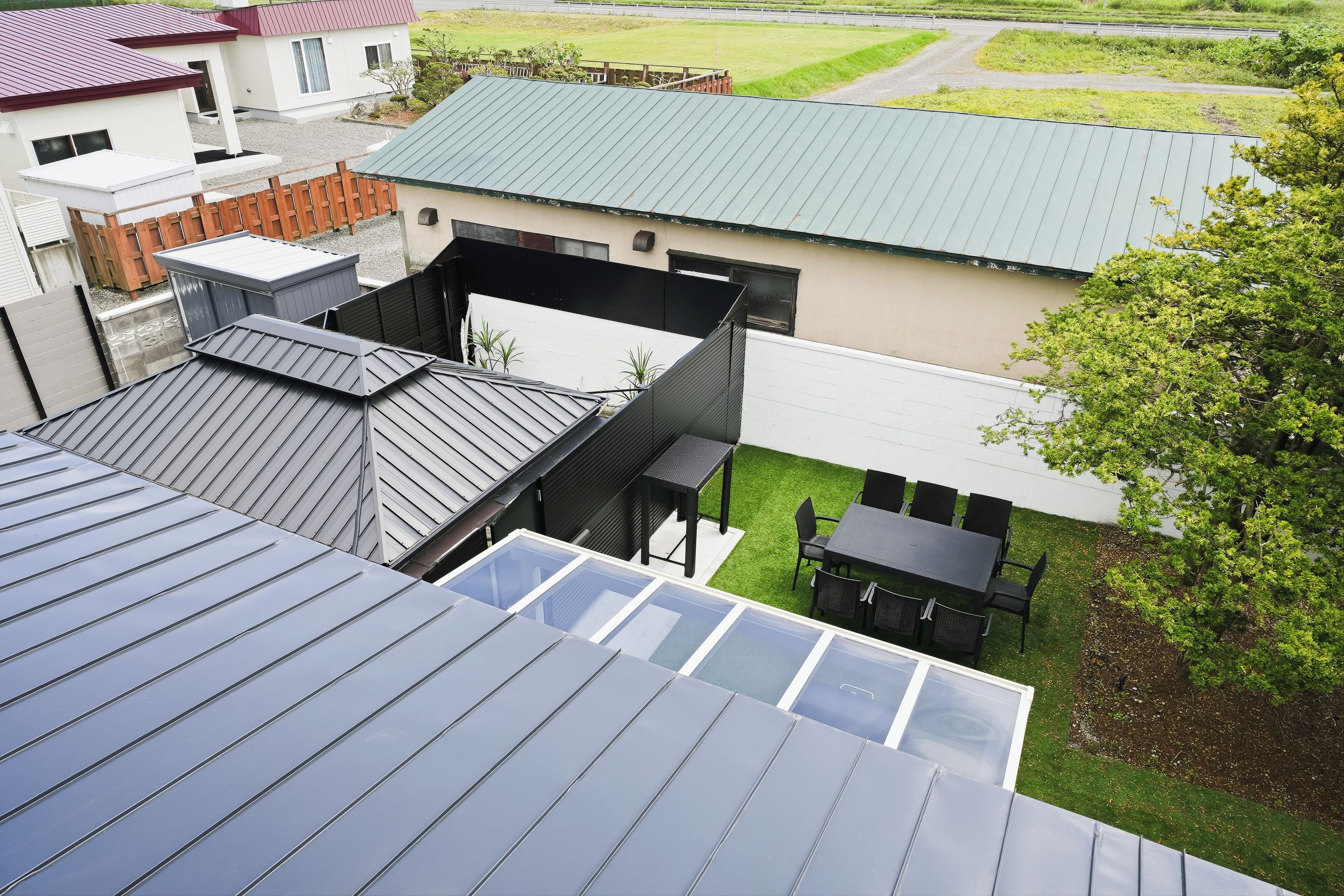 A residential building with multiple roofs, including a flat roof and a sloped roof with skylights.