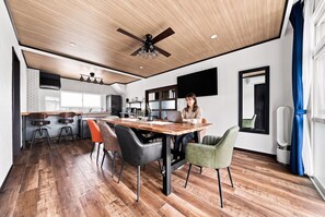 Une cuisine moderne avec un coin repas, un plancher en bois et un ventilateur de plafond.