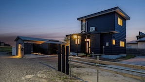 Een modern herenhuis met een donkere gevel, een zichtbare airconditioning en een goed verlichte entree.