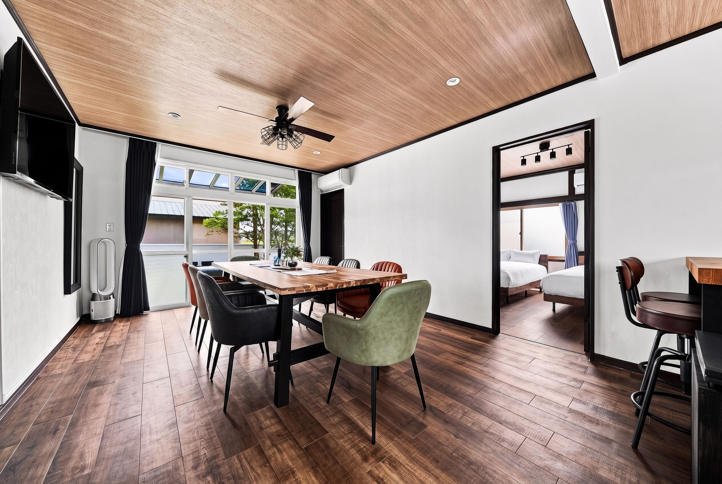 Un intérieur moderne comprenant un coin repas, un ventilateur de plafond et une vue sur l’extérieur.