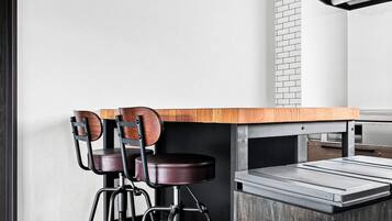 A modern kitchen with a wooden countertop, two bar stools, and a built-in brick oven.