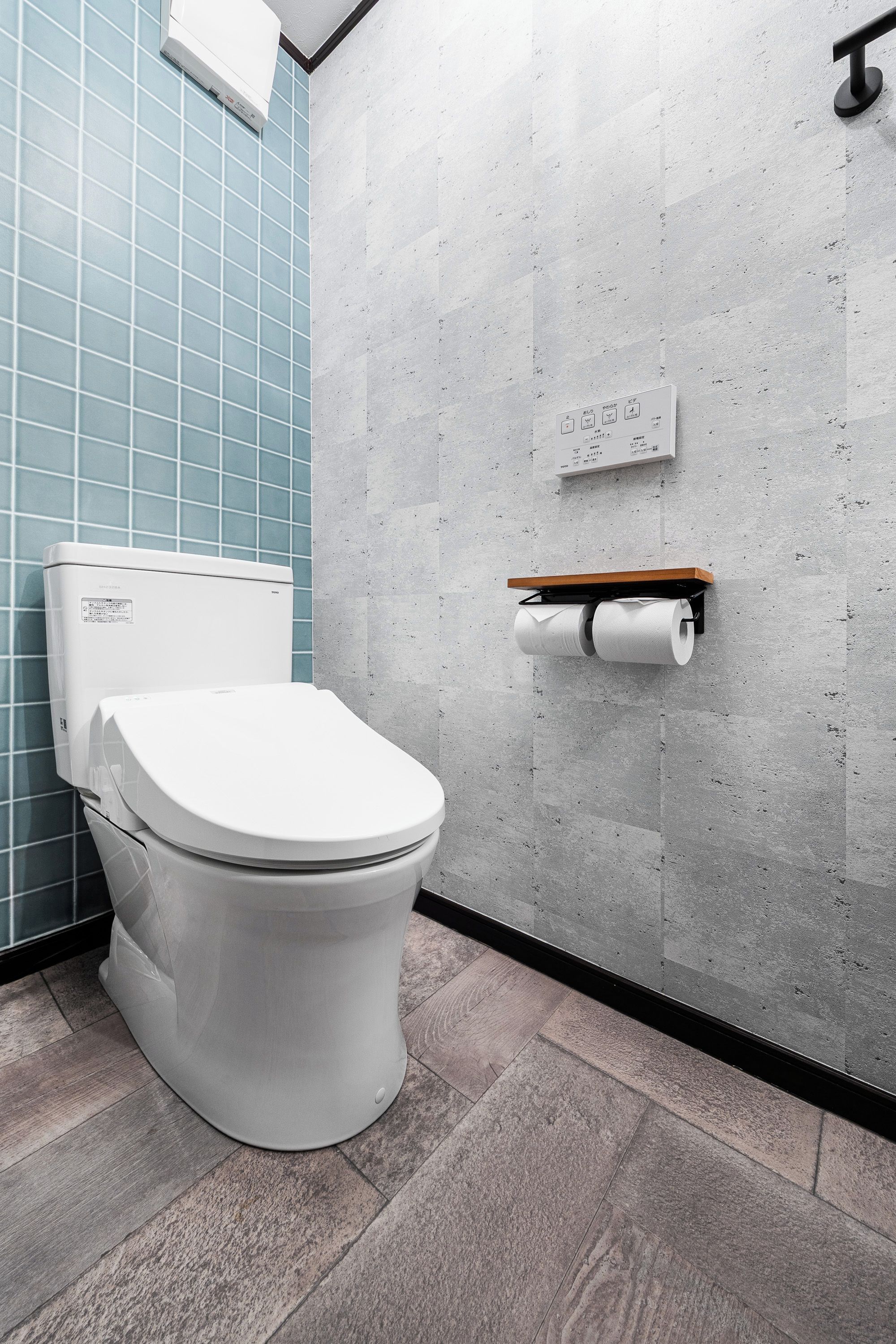 Moderni kylpyhuone, jossa on wc, pyyheteline ja wc-paperiteline.