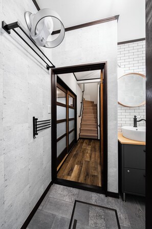 Un baño moderno con suelo de madera, un lavamanos blanco y un espejo con marco de madera.