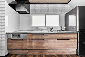 A modern kitchen with a stainless steel sink, wooden cabinetry, and a large window above the countertop.
