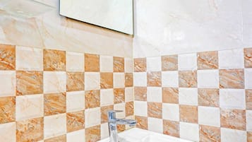Ein Badezimmer mit einem weißen Waschbecken, einer Fliesenrückwand mit Schachmuster und einem Spiegel darüber.