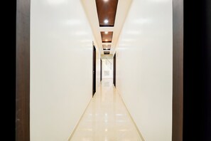 A modern, well-lit hallway with a glossy floor, leading to a staircase and a door at the end. - Super Hotel O Dabha Hilltop (Nagpur)
