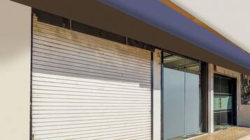 A building facade with a closed roller shutter door and a glass entrance.