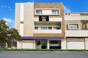 Un edificio moderno con fachada plana, un cartel que indica que ofrece servicios de empresa y un acceso con portón.